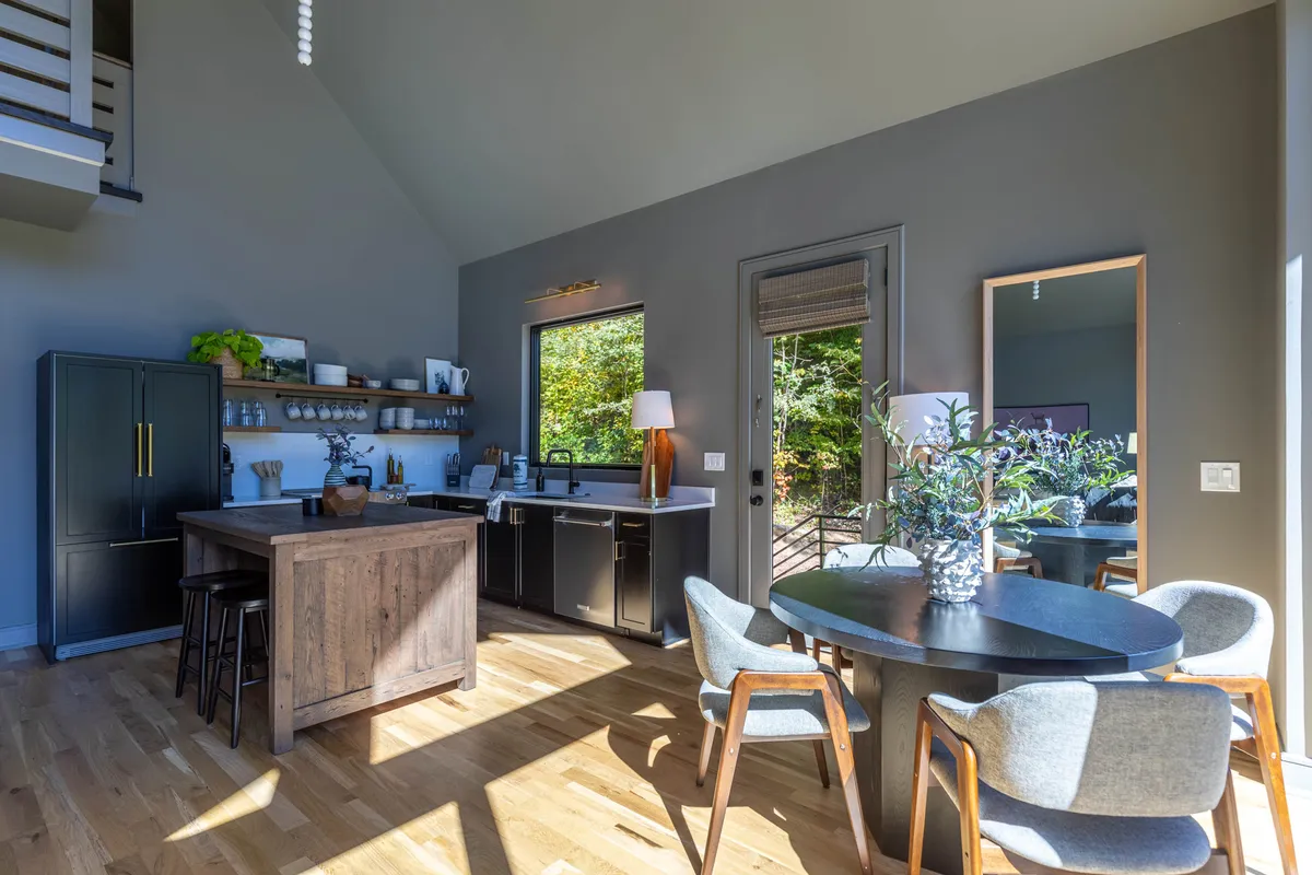 A well-equipped kitchen and dining area with a central island, large windows letting in abundant natural light, and a welcoming setting for cooking or socializing. The space seamlessly connects with the living area, supporting a sense of openness.