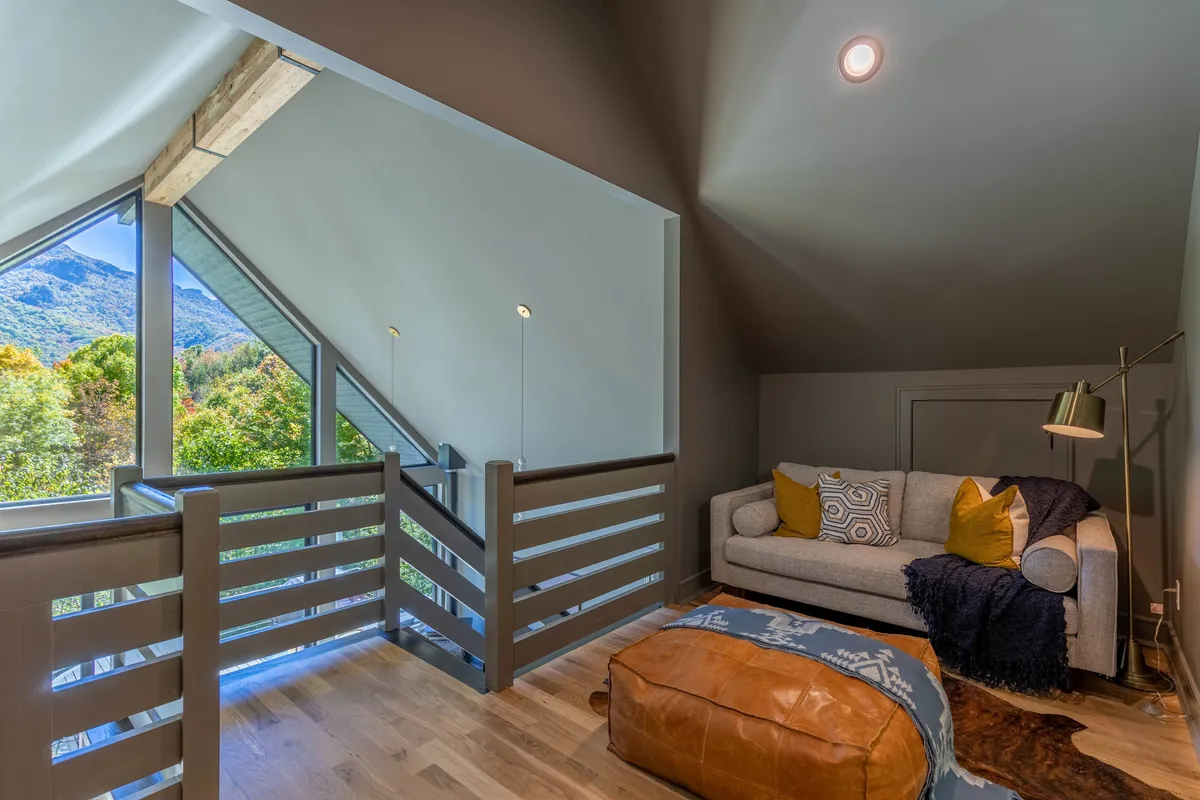 A cozy seating area featuring a sofa with decorative cushions, a view of the mountains through the window, and soft lighting. The inviting atmosphere is complemented by the visible proximity to the outdoors.